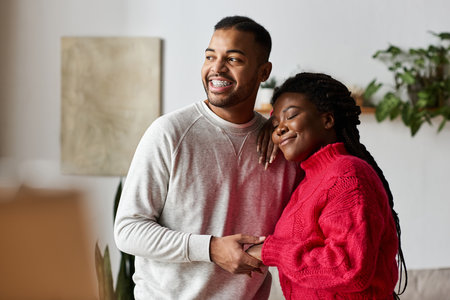 A happy couple in warm sweaters share loving glances while relaxing at home.の写真素材