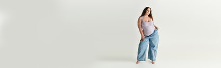 Chic young woman confidently poses in oversized denim while highlighting her fashion sense.の写真素材