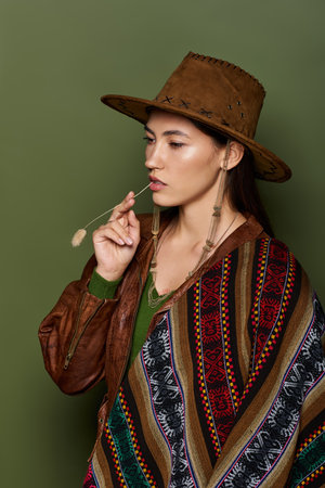 Beautiful young brunette woman wears a traditional outfit while holding a decorative stem.の写真素材