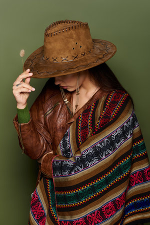 A stunning brunette embraces her culture with a beautifully patterned poncho and hat.の写真素材