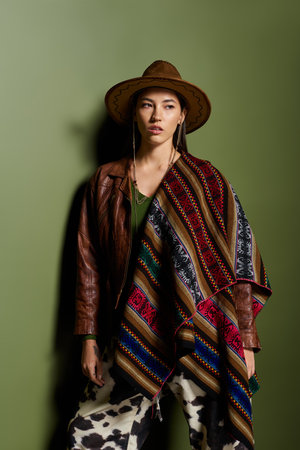 Brunette woman showcases her fashion sense with unique attire while striking a pose indoors.の写真素材
