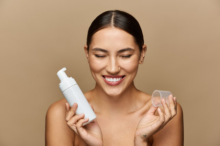 Brightly lit space captures a young woman happily showcasing her skincare routine with confidence.の写真素材
