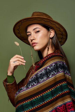 A confident young brunette shines in a vibrant, traditional outfit, posing gracefully.の写真素材