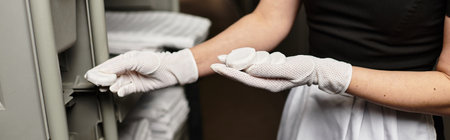 Beautiful young woman skillfully arranges delicate items in a modern kitchen setting.の写真素材