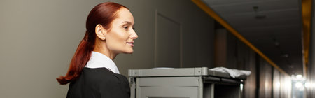 Beautiful young woman in a uniform walks confidently down a hotel corridor.の写真素材