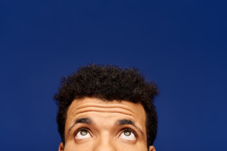 A handsome man looks thoughtfully upwards, his expression hinting at curiosity and wonder.の写真素材