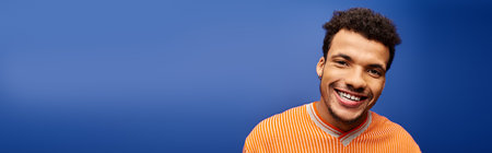 Charismatic young man with a warm smile enjoying his time in a stylish, colorful space.