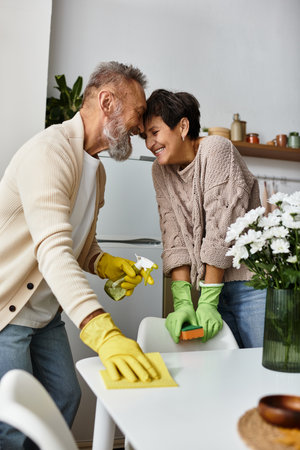 A mature couple shares laughter while cleaning their kitchen, showcasing love and teamwork.
