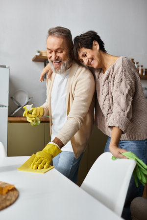 A mature couple enjoys cleaning their kitchen, laughing and bonding over shared tasks and smiles.の写真素材