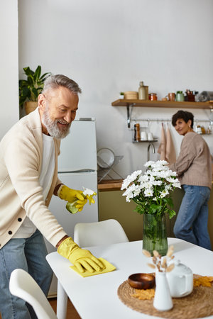 Senior couple shares a joyful moment as they clean and organize their cozy kitchen space.の写真素材