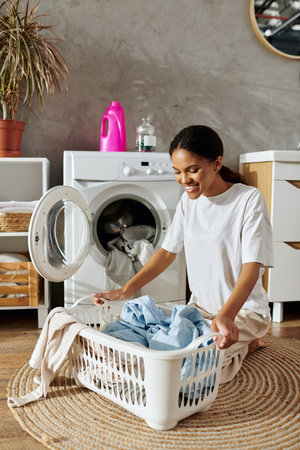 A young African American woman happily organizes her laundry in a stylish apartment interior.の写真素材