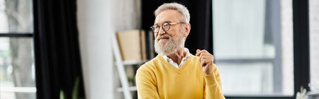 A mature handsome man with a gray beard is smiling and enjoying his time in a stylish room.の写真素材