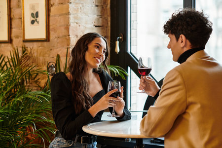 A beautiful couple toasts with wine, sharing smiles on a special valentines day evening.の写真素材