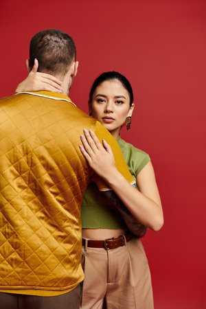 A beautiful couple in trendy attire showcases their love against a vibrant backdrop.