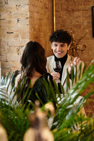 A couple enjoys a romantic dinner, laughing and sharing a glass of wine at a cozy restaurant.の写真素材