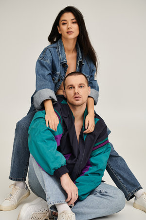 A beautiful couple in trendy outfits enjoys a romantic moment in a studio setting, radiating love.の写真素材