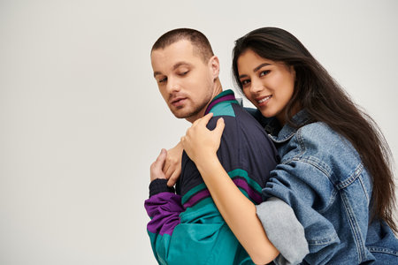 A beautiful young couple dressed in fashionable clothes embraces each other, radiating love.の写真素材