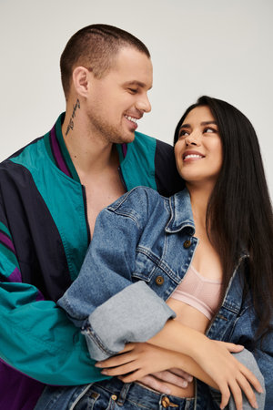 A young couple embraces each other, radiating joy and love while dressed in trendy clothing.の写真素材