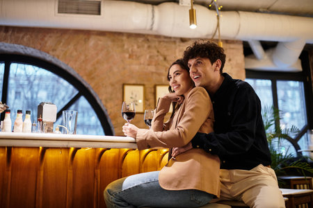 A young couple enjoys a romantic evening in a restaurant, sharing smiles and drinks.の写真素材