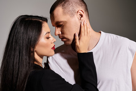 A charming couple in trendy outfits shares an intimate moment in a studio, celebrating love.の写真素材