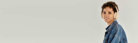 A joyful young woman in stylish clothes and headphones smiles brightly against a simple backdrop.の写真素材