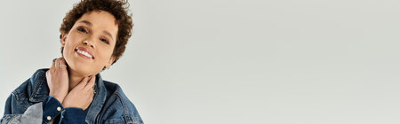 A young woman smiling brightly while adjusting her collar, showcasing her fashionable style.の写真素材