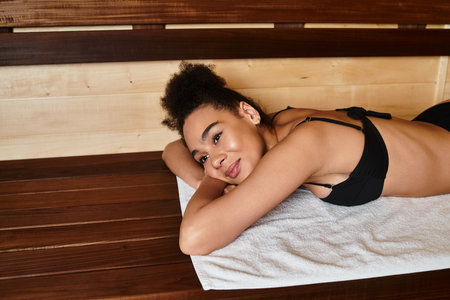 A beautiful young african american woman enjoys a peaceful moment in the spa, embracing relaxation.の写真素材