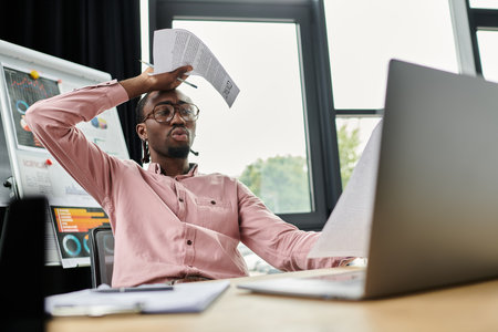 Young African American digital nomad multitasks at a modern workspace.