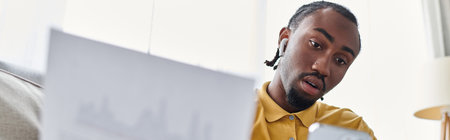 A focused young man surrounded by papers and tech embodies the nomadic work life.の写真素材