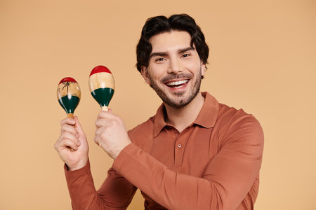 A handsome young man smiles brightly while holding colorful maracas, radiating joy and energy.の写真素材