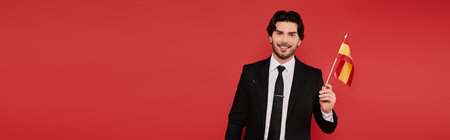 A smiling young man with dark hair proudly holds a small Spanish flag.の写真素材