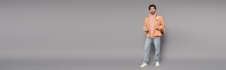 Confident young man stands with arms relaxed, showcasing a laid back style in a modern setting.の写真素材