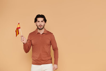 A young handsome man proudly holds a colorful flag in a bright, warm toned backdrop, exuding joy.の写真素材