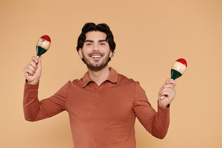 Bright atmosphere created as a handsome young man plays maracas with a cheerful smile.の写真素材