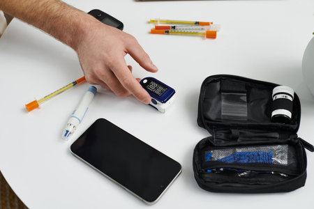 Young man checks blood sugar levels while maintaining his diabetes routine at home.の写真素材