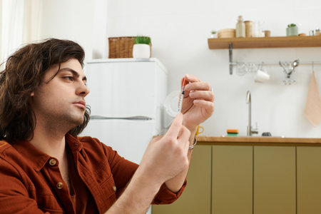 Caucasian man with diabetes checks his blood sugar levels in a modern apartment setting.の写真素材