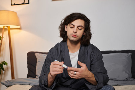 Young man with diabetes practices self-care in a modern apartment, showcasing his routine.の写真素材