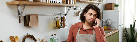 A good looking young man engaged in conversation on the phone while preparing food at home, banner