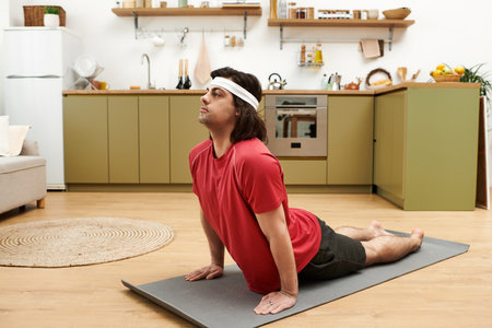 Young man showcases his daily fitness routine on a mat in a stylish apartment kitchen.の写真素材