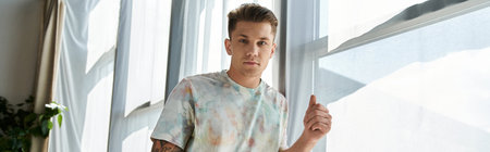 A young handsome man strikes a confident pose in a bright room.の写真素材