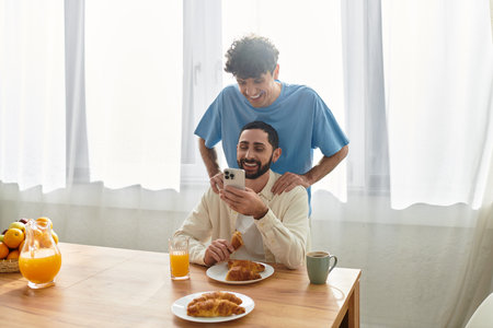 Casual breakfast filled with joy as two men savor food and each others company in their apartment.の写真素材