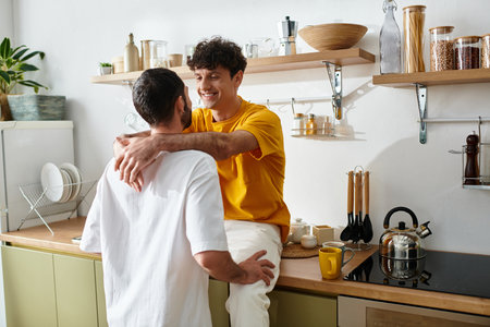 Two men in casual attire embrace playfully in their stylish home kitchen.の写真素材