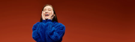 A vibrant and stylish woman smiles widely, showcasing her joy with hands on her cheeks.