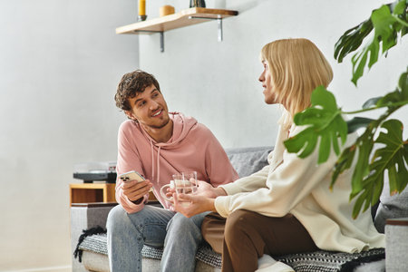 Two men sit together in a warm living room, sharing drinks and laughter, enjoying their time.の写真素材