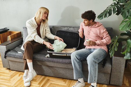 Two men share joyful moments while packing essentials for their upcoming trip in a stylish space.の写真素材
