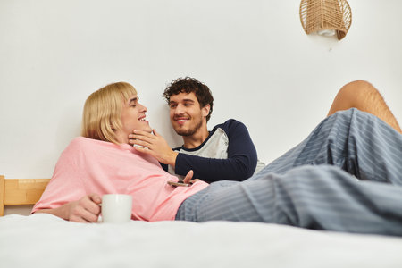 A tender interaction unfolds as two men enjoy each others company while relaxed in bed.の写真素材