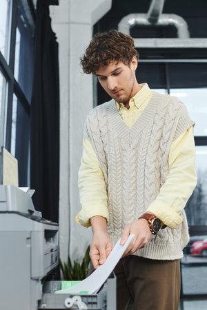 Curly-haired professional organizes documents in a bright corporate environment.