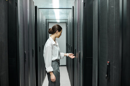 A skilled IT specialist in a white shirt adjusts equipment in a modern server room.