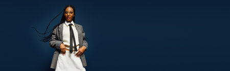 A young woman confidently poses in a chic ensemble with playful hair movements in a bold setting.の写真素材