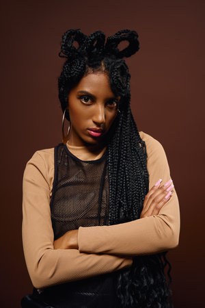 A young woman flaunts her stylish outfit and intricate braids, radiating confidence.